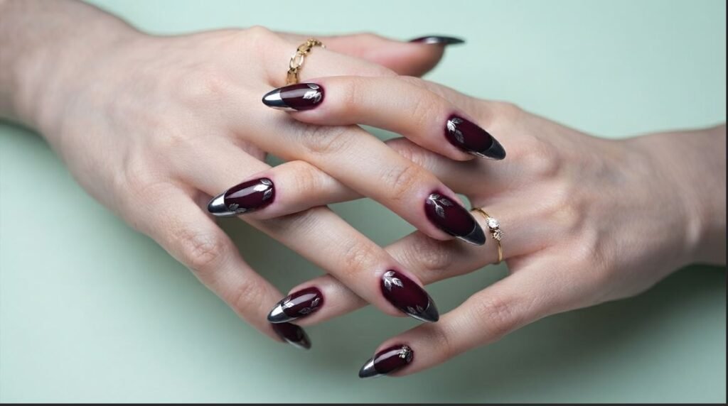 Burgundy stiletto nails with solid metallic silver tips on an 18-year-old hand with very white skin.