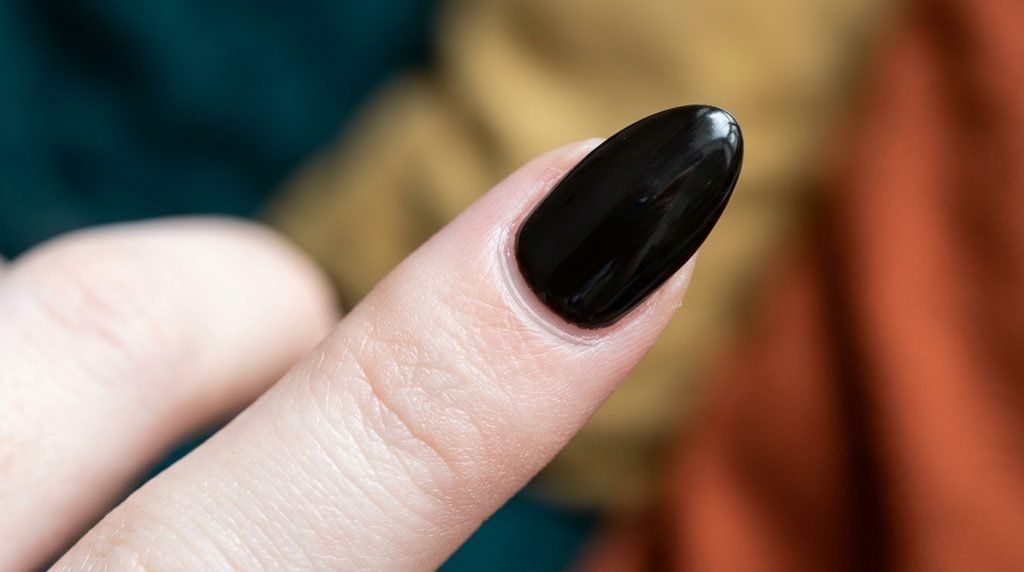 Extreme macro view of black gel polish applied cleanly near the cuticle without flooding.