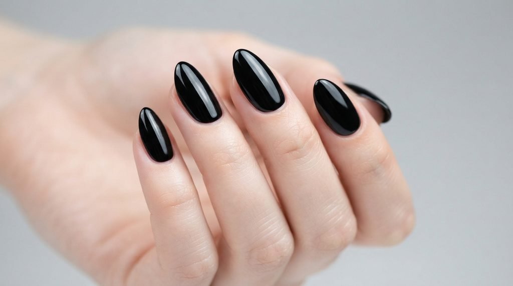 Macro photograph of perfectly painted black gel nails on fair skin showing neat cuticles.