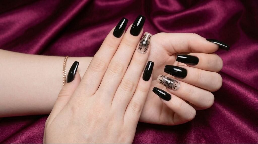 Close-up of a female hand with smooth white skin showing coffin nails with black floral art over a nude base.