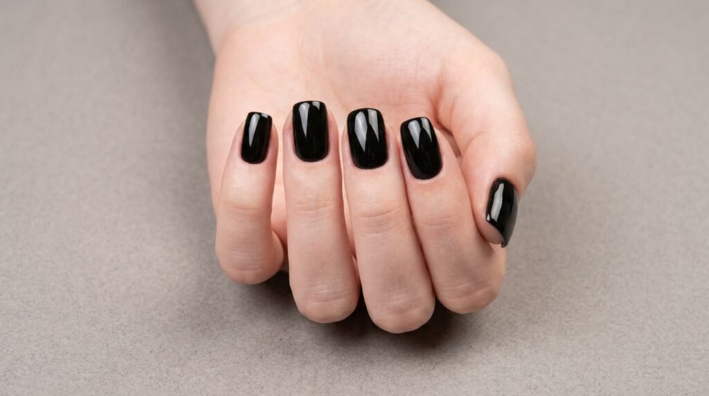 Perfectly manicured glossy black gel nails on 18 year old hand with smooth white skin.