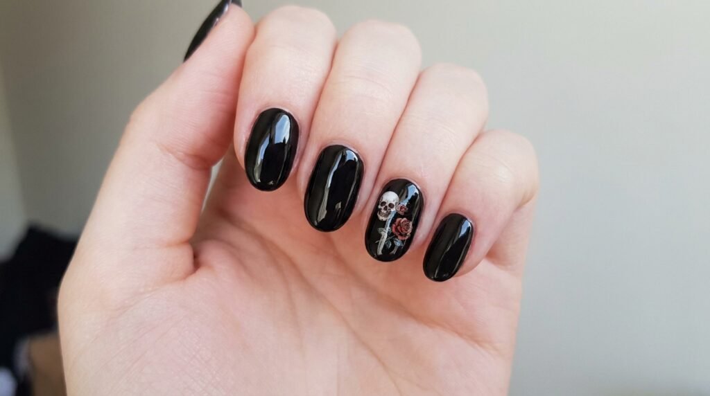 Black gel nails with skull and rose slide decal art on female hand with very white skin tone.