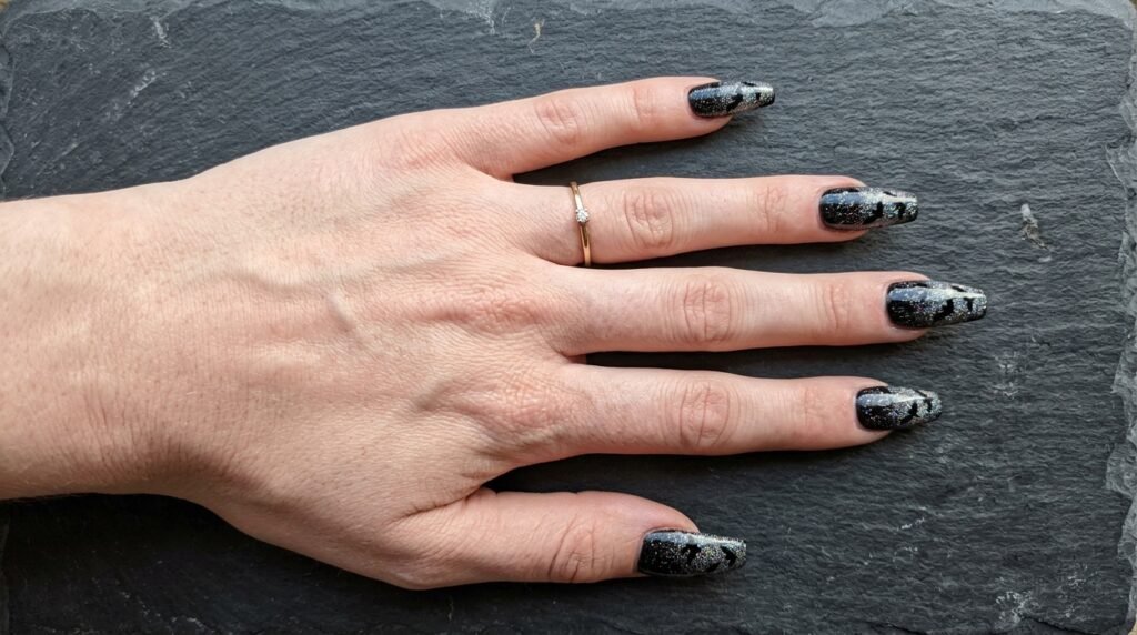 Top down view of coffin-shaped nails with bat silhouettes on female hand with white skin.