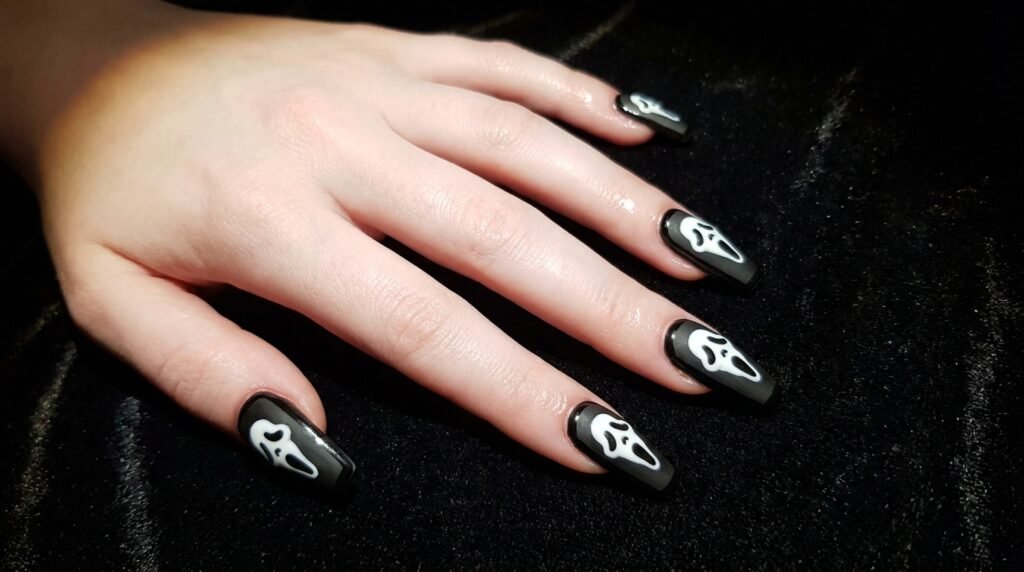 Long coffin nails with a ghostface mask accent on an 18 year old hand with very white skin.