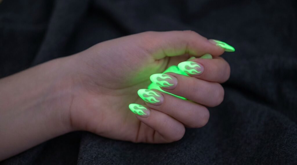 Almond shaped nails with radioactive green glow-in-the-dark flame art on smooth white hand.