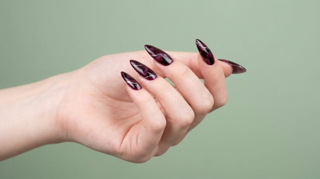 Marbled red and black stiletto nails with silver veins on an 18-year-old hand with very white skin.