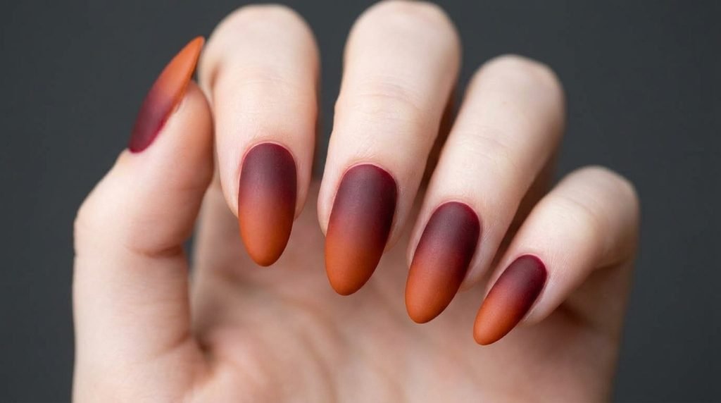 Extreme macro view of a single almond nail on an 18-year-old female finger with white skin showing a smooth matte gradient.