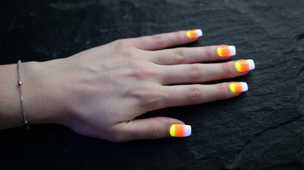 Square nails with glowing yellow, orange, and white candy corn gradient on dark slate.