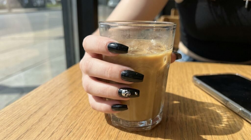 Wearable daily goth manicure with glossy black nails and single silver skull accent finger.