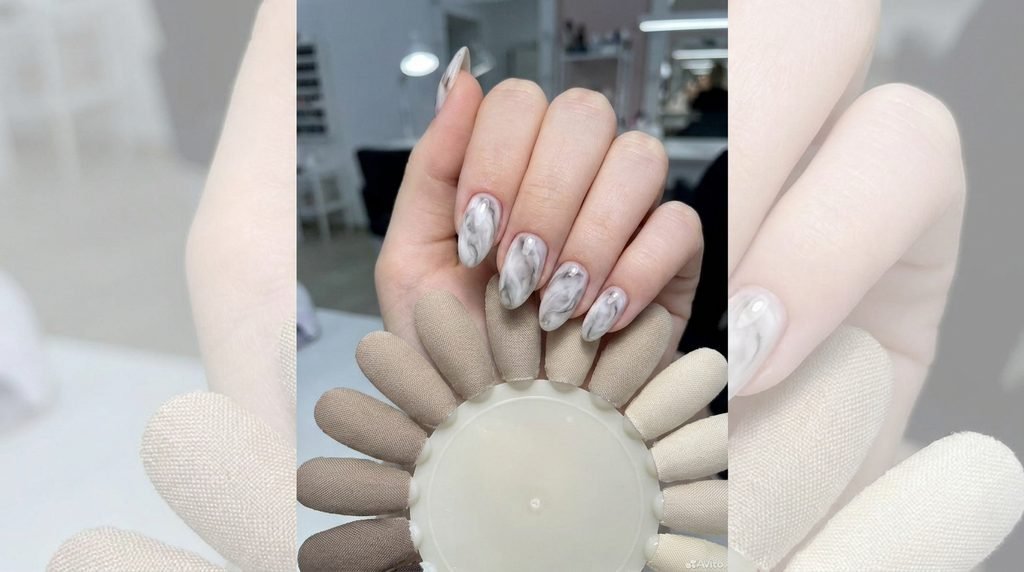 Perfectly finished almond smoky black marble nails held against a color swatch wheel by an 18-year-old female hand.