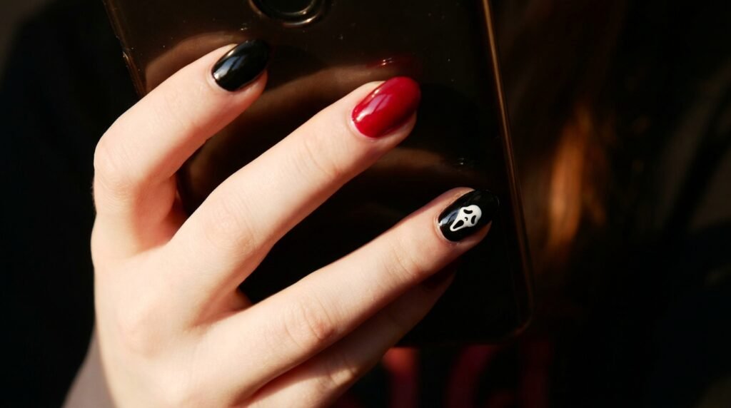 Alternating red and black nails featuring a ghost mask design on light white skin.