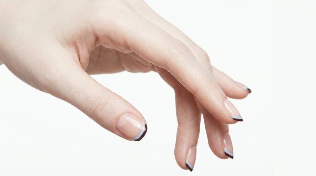 Minimalist short squoval nails on a young female hand with very white skin, featuring clear polish and thin double micro French tips in blue and brown.