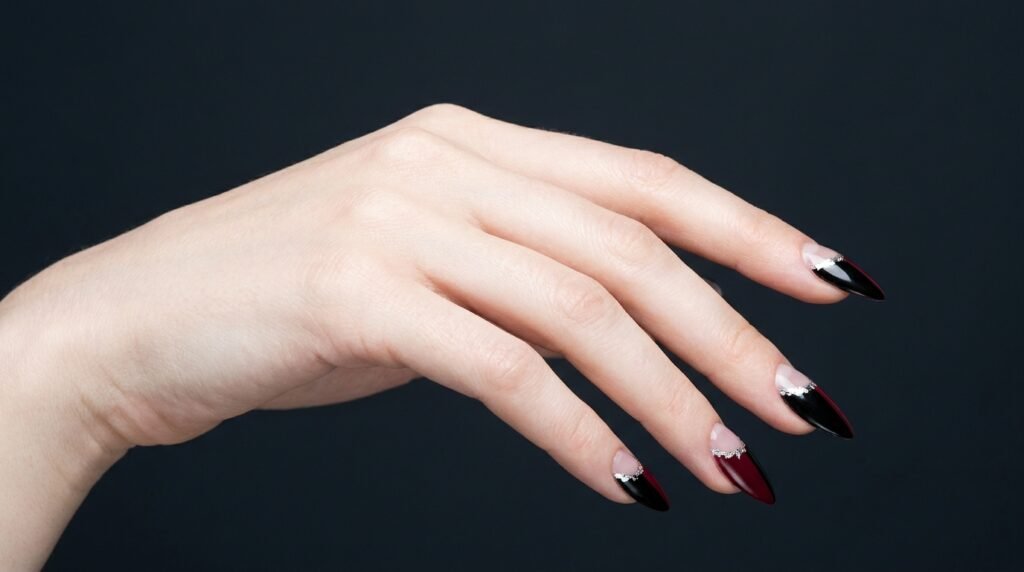 Negative space cuticle cutout with silver floral borders on dark stiletto nails on very white skin.