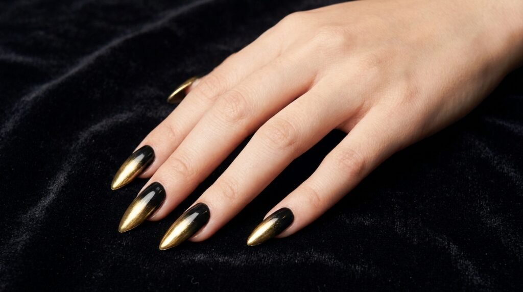 Long stiletto nails featuring liquid gold chrome ombré faded into a jet-black base polish.