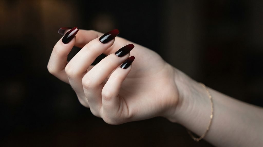 A detailed close-up of long coffin nails with a smooth gradient fade from black to deep red.