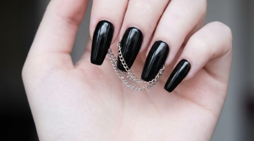 Silver micro chains connected across black acrylic nails on female hand with smooth white skin tone.