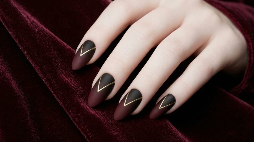 Elegant close-up of matte black to burgundy ombré almond nails on a white female hand (18), resting on burgundy silk.