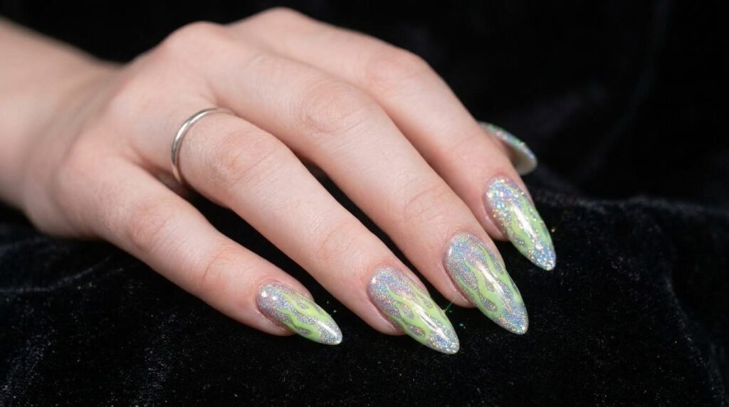 Holographic glitter nails with neon green flame overlays on almond shape white female hand.