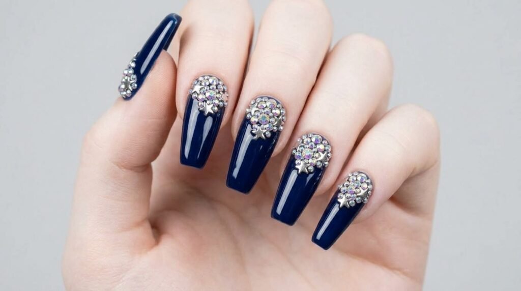 Rhinestones and silver star charms on long dark navy coffin nails on an 18-year-old female hand with white skin.