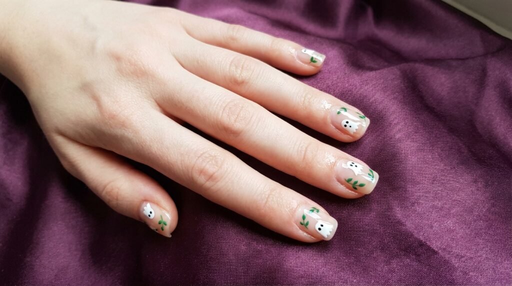 Natural short squoval nails with micro ghost doodles and tiny leaf sprigs on white skin.