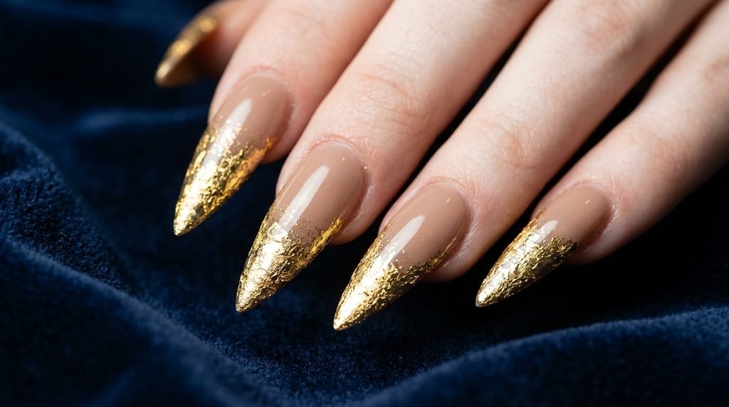 Long stiletto mocha nails with gold leaf tips on an 18 year old hand with very white skin.