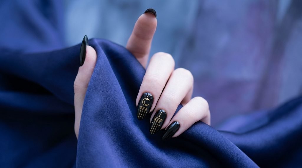 Long almond black nails featuring intricate gold linework of High Priestess card symbols against flowing deep indigo silk.