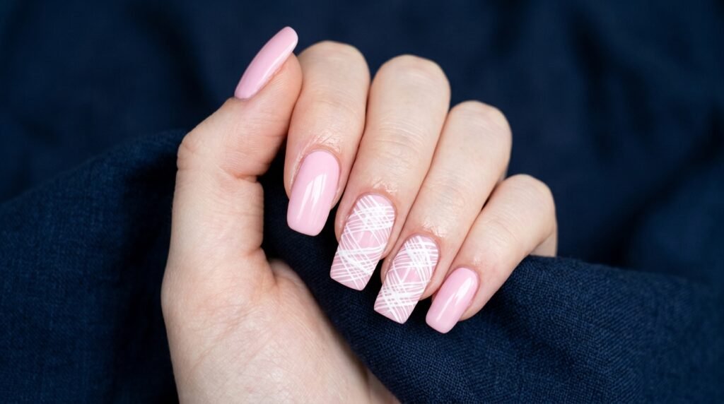 Long squoval baby pink nails with white crisscross mummy wrap lines on an 18-year-old female hand with pale skin.