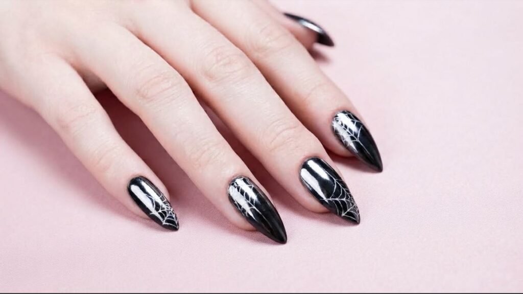 High shine black chrome stiletto nails with white web art on an eighteen year old female hand.