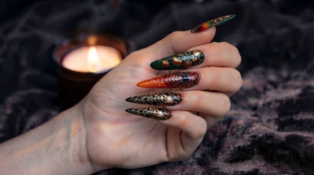 Highly detailed close-up photography of almond-shaped stained glass halloween nails featuring jewel tones and gold outlines on an 18-year-old female hand with very white skin against a dark velvet background.