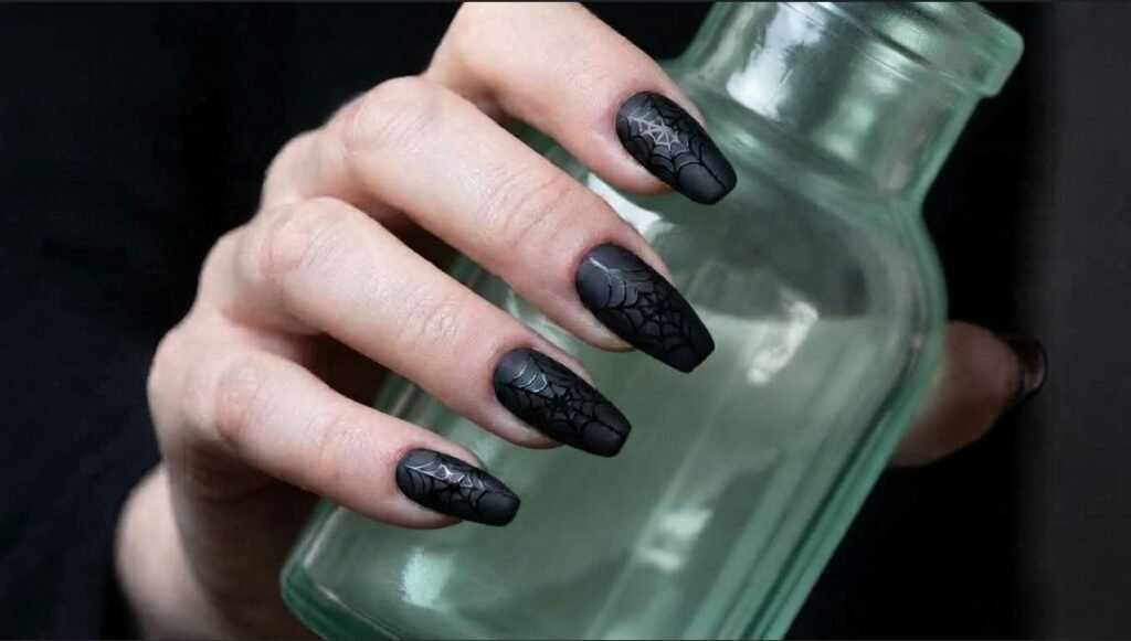 Matte black coffin nails on a white skinned eighteen year old female hand with glossy web detail.