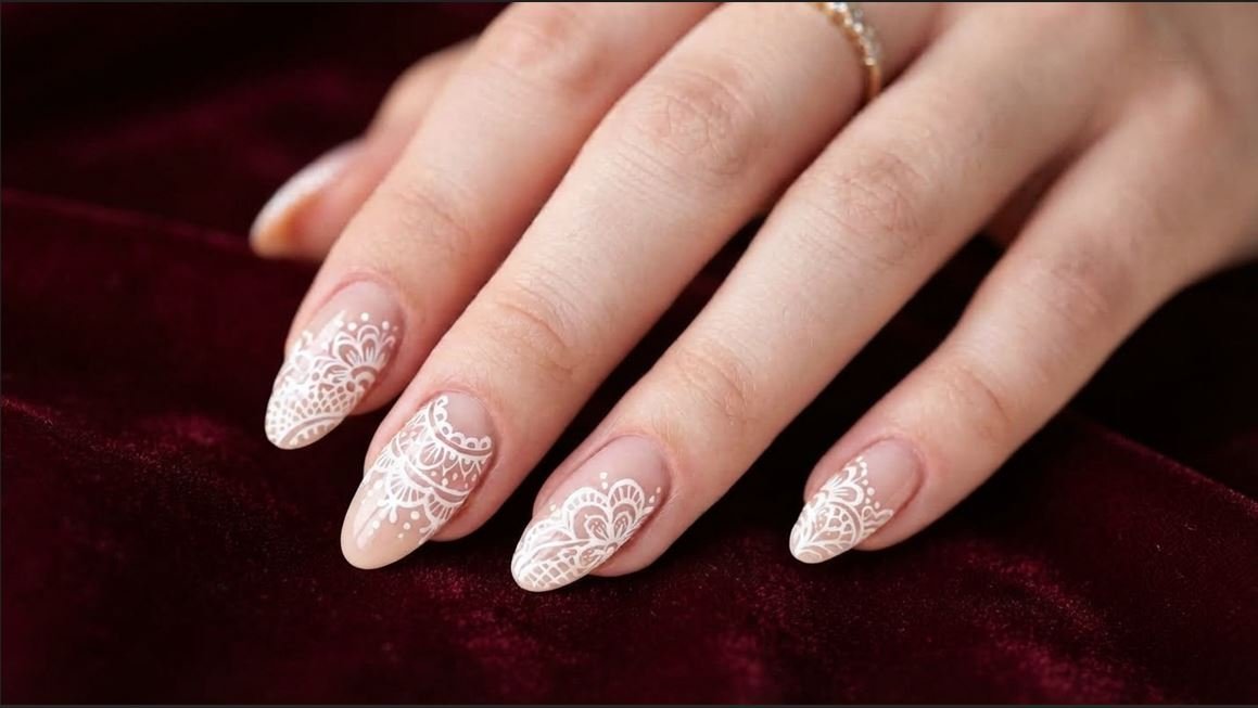 Close up of an 18-year-old female hand with very white skin showing white doily lace nail art on almond nails.