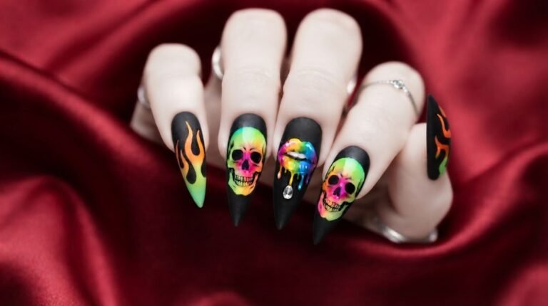 Close-up of 18 year old female hand with very white skin showing long stiletto nails with neon skull artwork on matte black polish.