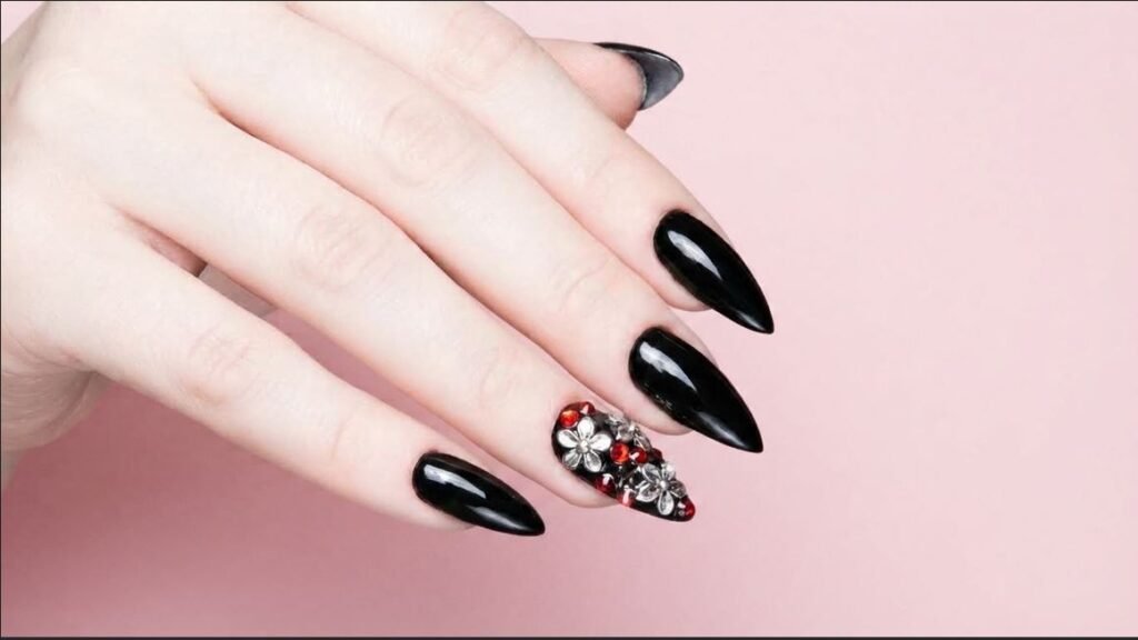 Rhinestone and floral charm accent nail paired with black stiletto nails on very white skin.