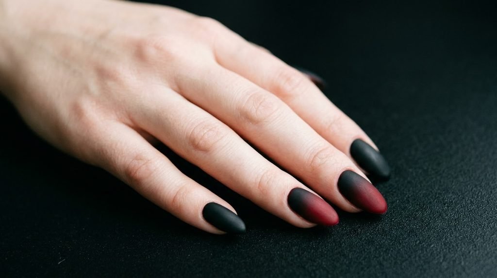Highly pigmented black and red matte nails on an 18-year-old female hand.