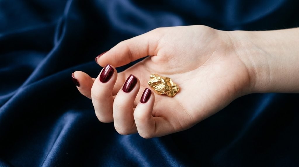 Squoval velvet merlot nails on very white skin resting on midnight blue satin.