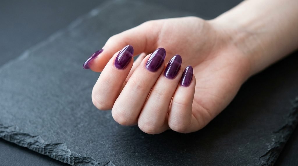 Translucent violet jelly nails on an 18-year-old female hand with very white skin resting on charcoal slate.