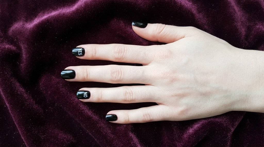 Short square black nails with white spirit board accents on an 18-year-old female hand with white skin.