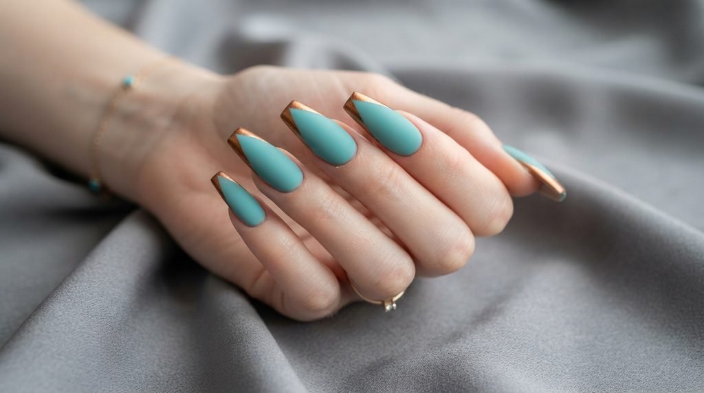 Long coffin nails painted matte teal with bronze tips on an 18-year-old female hand with white skin.