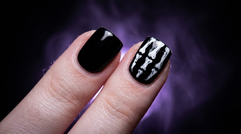 Close-up of an 18-year-old female hand with short square nails painted with glossy black, one nail featuring simple white bone line art, against a dark background with a diffused soft violet glow.