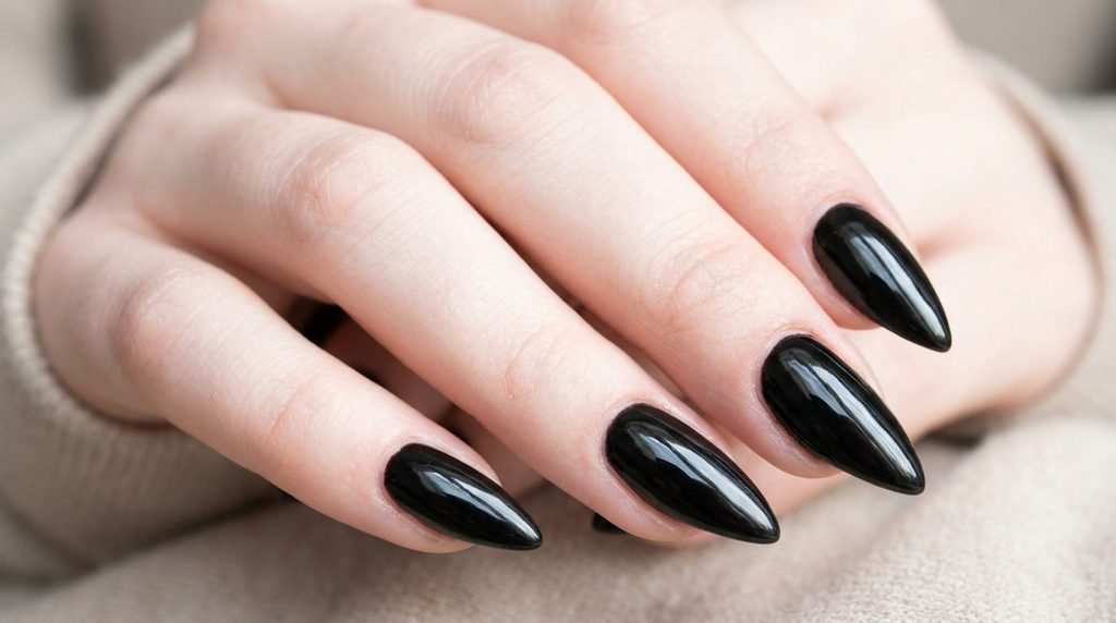 Neat cuticle boundary on black stiletto gel nails, 18-year-old female hand with very white skin.