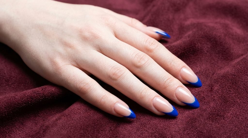 Cobalt blue French tips on long almond nails with very white skin.