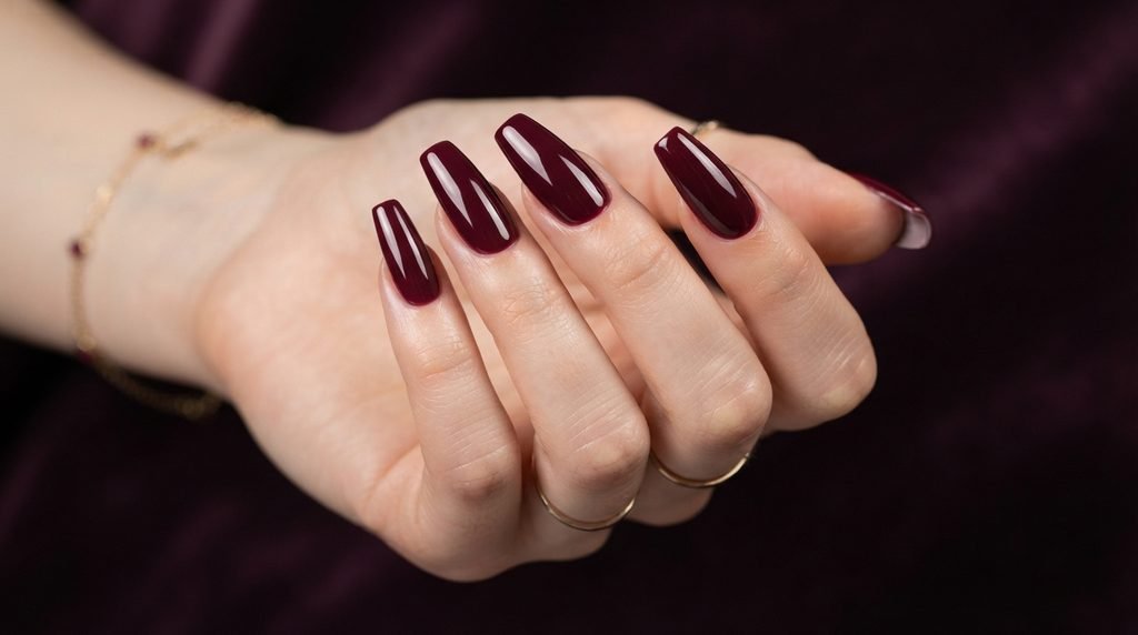 Long coffin nails with smooth deep merlot red polish on very fair skin.