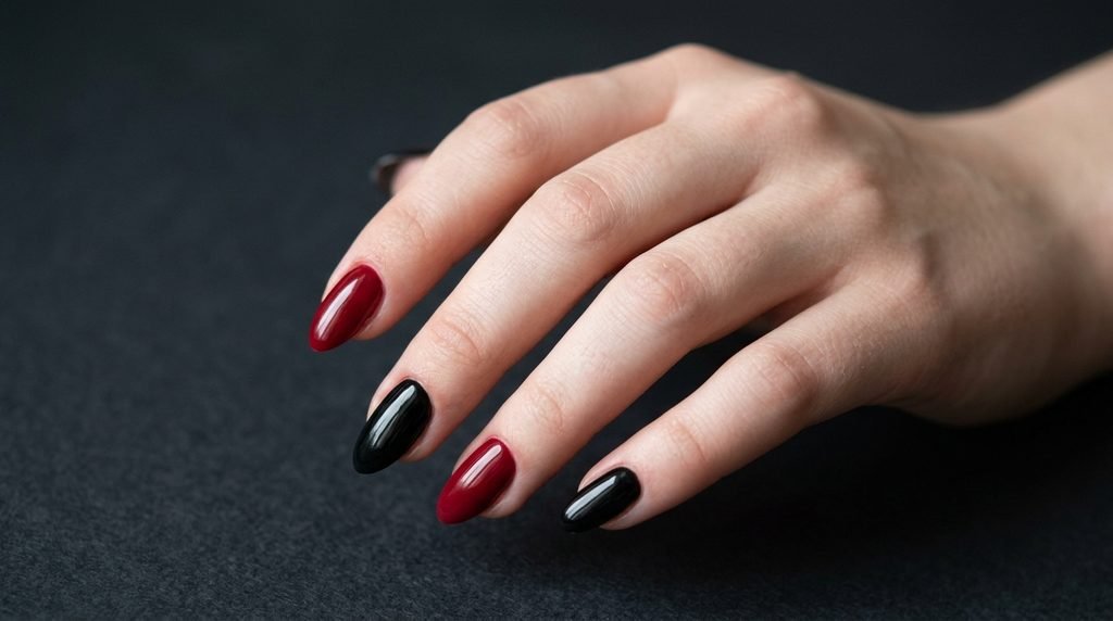 Pitch-black and crimson red two-tone nails on an 18-year-old hand with smooth white skin.
