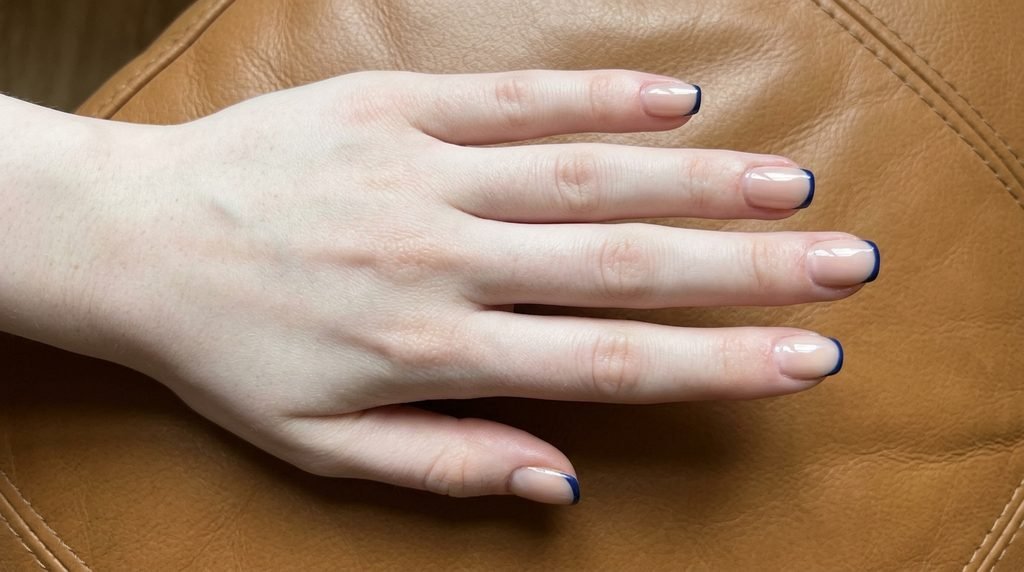 Navy blue French tips on short square nails with very white skin.