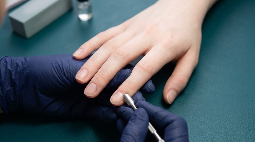 Prepped natural fingernails on fair skin displayed against a dark teal background.