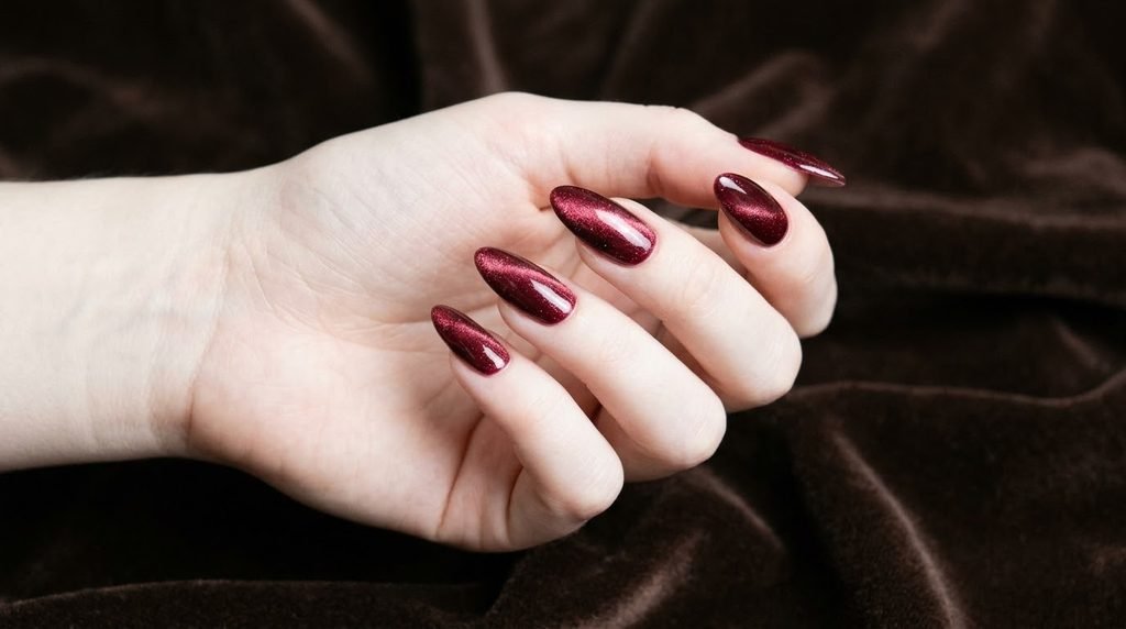 Long almond velvet merlot nails on an 18-year-old hand with very white skin on brown velvet.
