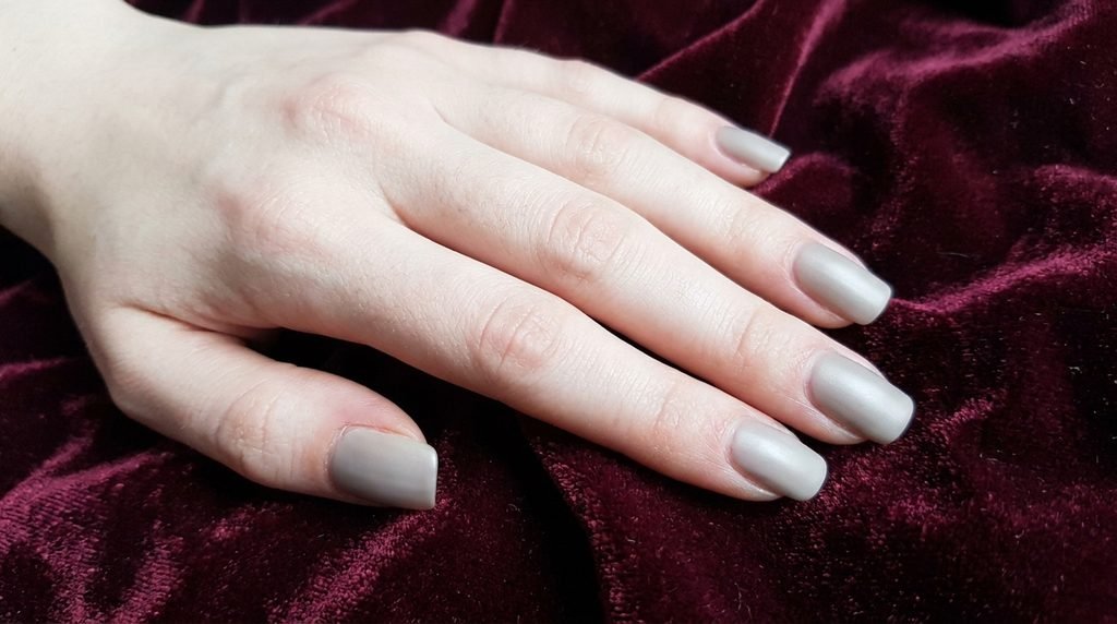 Cashmere nails in soft greige on medium square nails over dark wine-red velvet background.