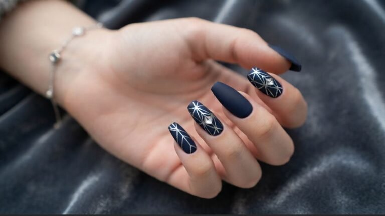 A close-up photograph of an 18-year-old female's very white, smooth-skinned hand with long coffin nails. Most nails are deep matte midnight navy; one index finger is a glossy geometric silver accent nail. The hand rests against a grey sweater.