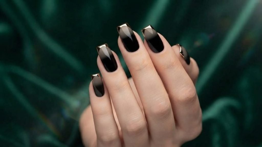 Extreme close-up of square nails with high-gloss black polish and a sharp, reflective gold chrome line at the cuticle.